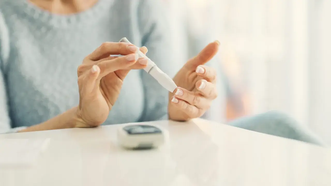 Mujer se pincha el dedo con un glucómetro. La diabetes es hereditaria, y el control es clave.
