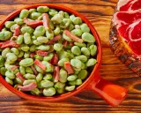 Un plato de habas tiernas con trocitos de jamón, ideal para quienes preguntan qué es el favismo y buscan recetas.