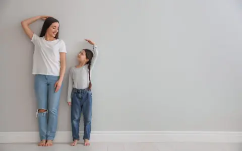 Madre e hija miden su altura. La estatura se hereda del padre o madre, y esta niña parece estar heredando la de su madre.