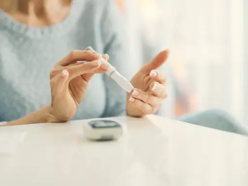 Mujer se pincha el dedo con un glucómetro. La diabetes es hereditaria, y el control es clave.