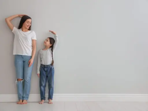 Madre e hija miden su altura. La estatura se hereda del padre o madre, y esta niña parece estar heredando la de su madre.