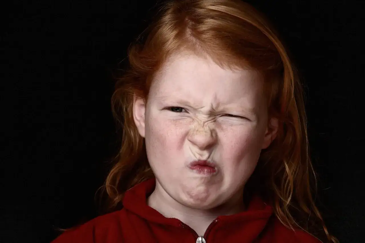 Ni&ntilde;a pelirroja con pecas hace una mueca. Podr&iacute;a ser una expresi&oacute;n facial involuntaria, como a veces ocurre con el s&iacute;ndrome de Tourette en ni&ntilde;os.